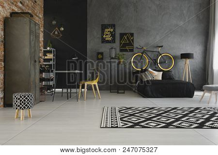 Real Photo Of A Modern, Open Space Apartment Interior With A Bicycle On The Bedhead Of A Black Bed A