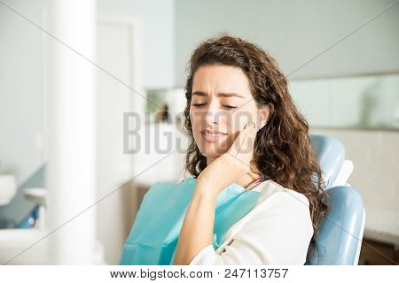 Young Woman Suffering From Toothache While Sitting On Dental Chair In Clinic