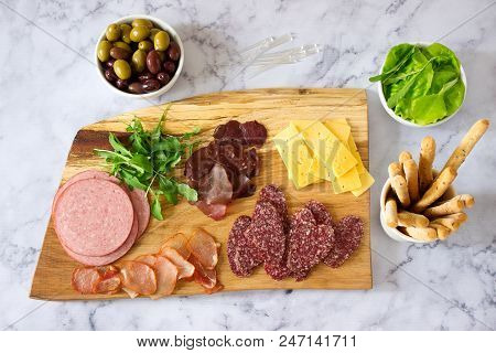 Appetizer Table For Wine Or Beer With Sausages, Dried Meat And Cheese, Served With Grissini, Herbs A