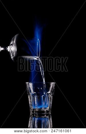 Close Up View Of Pouring Burning Sambuca Alcohol Drink Into Glass Process On Black Background