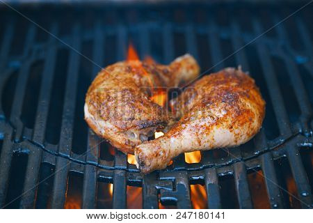 chicken legs spiced by special spice blend on bbq grill with flame