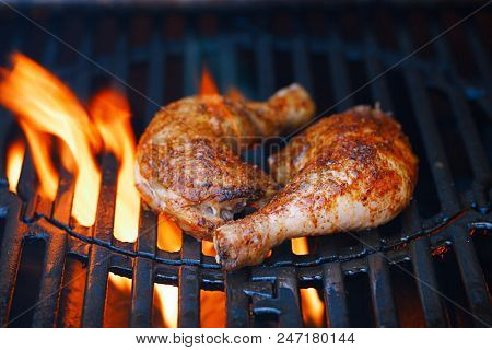 chicken legs spiced by special spice blend on bbq grill with flame