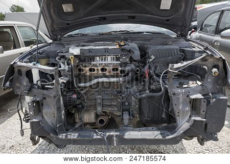 The Engine Compartment Of A Wrecked Car Reveals Missing Parts, Inlcuding The Bumper, The Radiator An