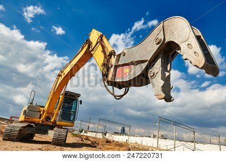 excavator crasher machine with crushing jaws at demolition on construction site