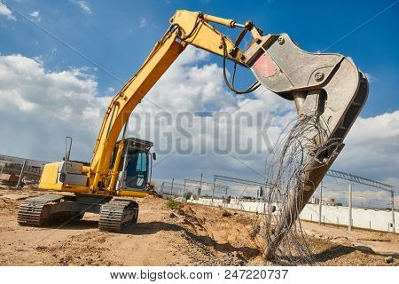excavator crasher machine crushing pole wit jaws on construction site