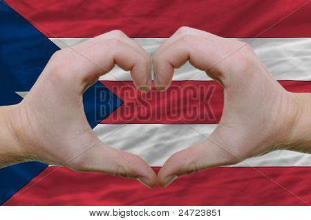 Srdce a láska gestem ukázal rukou nad vlajkou Puertoricol pozadí