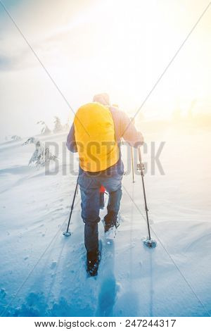 Climber hiking to a snowy hill. Climber with backpack climbs up mountains in winter