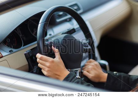 Girls Hands Are Aestetically Situated On The Black Steering Wheel In A Grey Car.