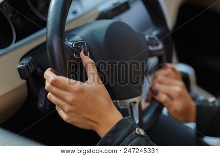 Girls Hands Are Aestetically Situated On The Black Steering Wheel In A Grey Car.
