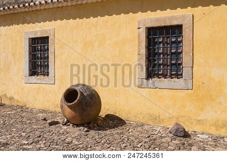 Yellow Wall Of An Old House, Part Of Castro Marim Castle. Windows With Stone Frames And A Grating. T