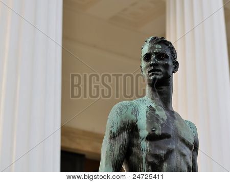 Bronze Statue af en sportslige mandlige krop foran et græsk tempel