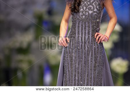 Female Model Walks The Runway In Grey Dress During A Fashion Show. Fashion Catwalk Event Showing New
