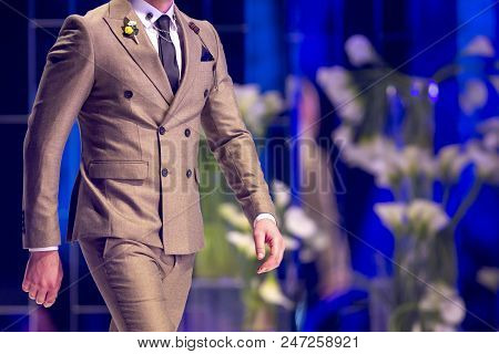 Male Model Walks The Runway In Beige Suit During A Fashion Show. Fashion Catwalk Event Showing New C