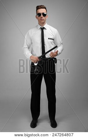Male Security Guard With Police Baton On Color Background