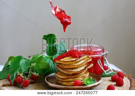 Delicious Pancakes With Raspberries On The Wooden Board. Raspberry Jam Poured On Pancakes.