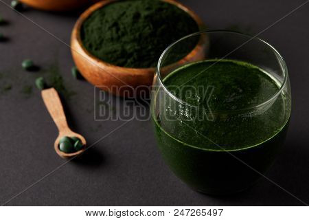 Close Up View Of Wooden Spoon, Glass Of Smoothie From Spirulina, Bowls With Spirulina Powder And Spi