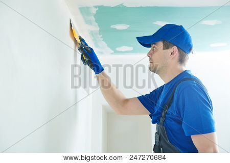 refurbishment. Worker spackling a wall with putty