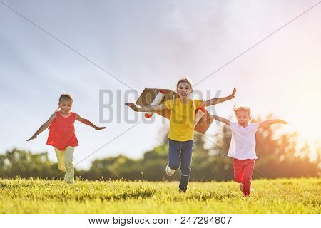 Little children playing astronaut. Girls fleeing and having fun in the park on sunset background. Kid in an astronaut costume dreaming of becoming a spaceman. Family games outdoors.
