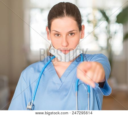 Young nurse woman wearing mask and stethoscope pointing with finger to the camera and to you, hand sign, positive and confident gesture from the front
