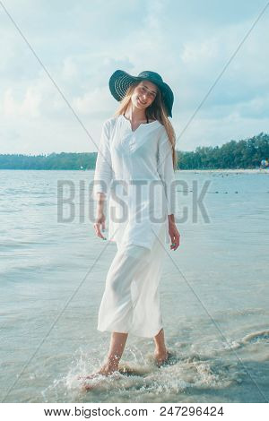 Handsome Girl In Hat On The Beach Background. Portrait Of A Woman In White Clothes And Balck Hat On 