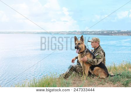 Man In Military Uniform With German Shepherd Dog Near River