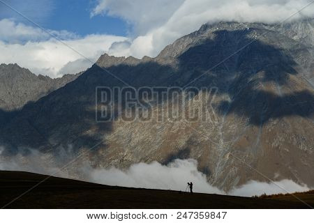 Landscape Photographer With Tripod And A Cardan Camera At Work In Mountains Against The Morning Mist