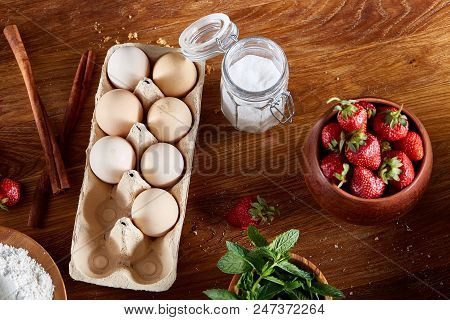 Strawberry Tart Covered With Whipped Sour Cream Surrounded By Organic Ingredients Over Wooden Backgr
