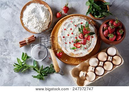 Strawberry Tart Covered With Whipped Sour Cream Surrounded By Organic Ingredients Over White Backgro