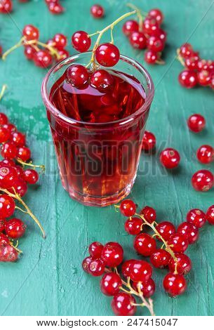 Redcurrant And Glass With Fruits And Drink Juice On Wood Table. Focus On Redcurrant In Glass,