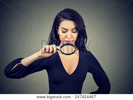 Young Woman Looking At Her Breasts Through Magnifying Glass