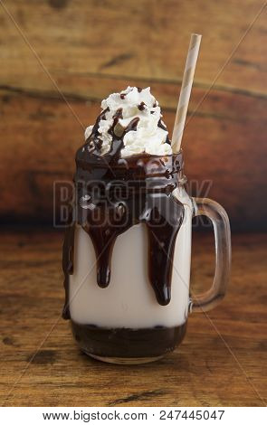 Chocolate Milk Shake Dripping With Chocolate Sauce On A Wooden Table