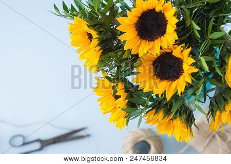 Bouquet Of Bright Sunflowers With Gift And Scissors On A White Table.