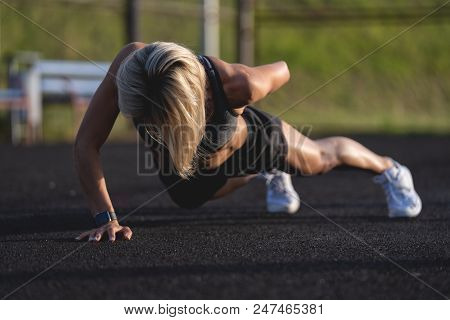Young Attractive Blonde Woman Doing Push Ups Outdoors At Sunsut Light