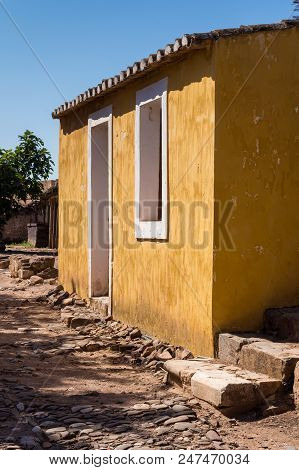 Yellow Wall Of An Old House, Part Of Castro Marim Castle. Windows With White Frame. Bright Blue Sky.
