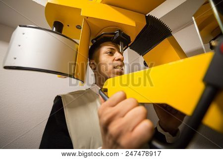 Crop View Of Black Male Making X-ray Examination Of Teeth On Colorful Machine.