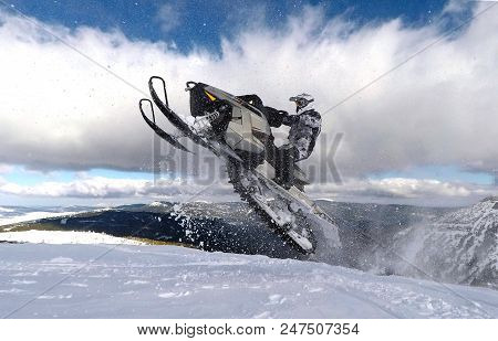 Man With A Snowmobile Jumping Between The Clouds