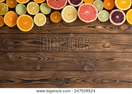 Border Of Assorted Halved Cut Fresh Citrus Fruit On A Wooden Background With Decorative Woodgrain An