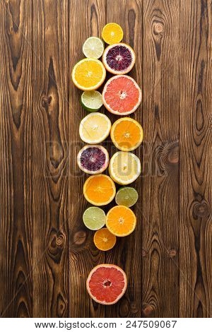 Overhead View Of Different Sliced Fruit In Shape Of Exclamation Mark On Wooden Background.