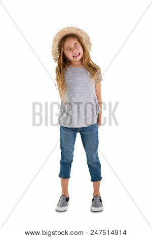 Stressed Little Girl With Long Blond Hair Wearing A Wide-brimmed Straw Hat Standing Baring Her Teeth