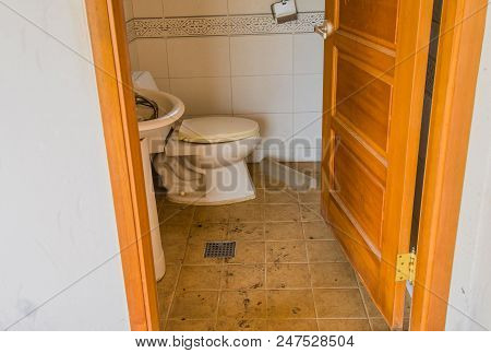 Grungy Half-bath With Sink Full Of Debris And Dirty Commode In Abandoned House.