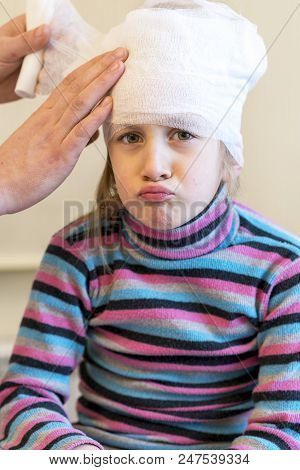 Doctor Makes A Bandage Of Young Girl's Head After Plastic Surgery. Verical Photo