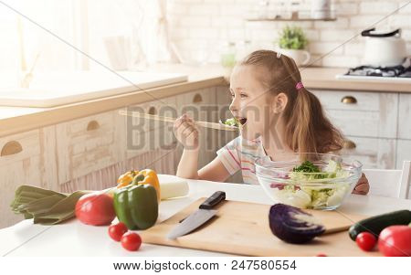 Hungry Little Girl Eating Fresh Salad In A Quiet, Secretly Came To Kitchen, Copy Space