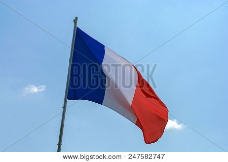 Flag Of France Against A Blue Sky With Clouds.