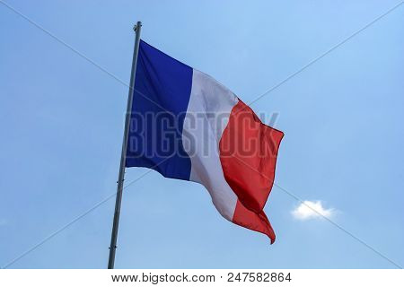 Flag Of France Against A Blue Sky With Clouds.