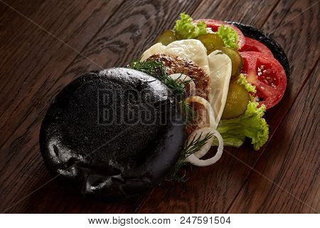 Black Burger On Vintage Wooden Background, Top View, Close-up, Selective Focus. Artistic Layout. Exo