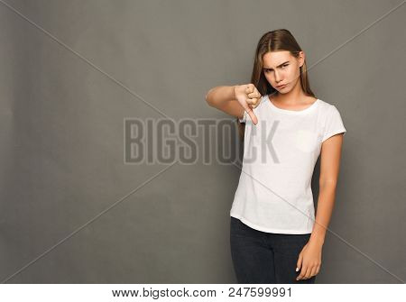 Woman Gesturing Thumb Down Sign. Young Blonde Girl Showing Negative Emotion, Symbolising Loss And Fa