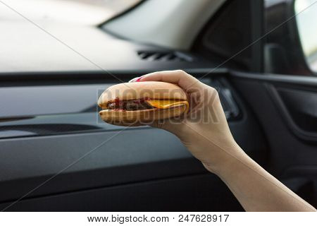 Beautiful Girl Holding A Cheeseburger With Her Hands, Close-up On A Blurred Background
