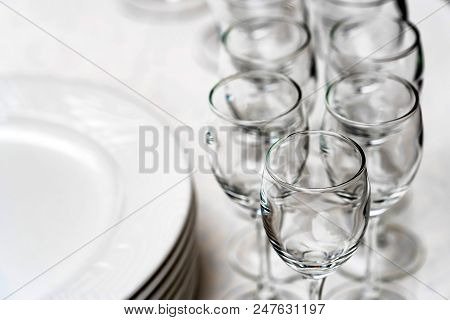 Close Up Empty White Plates Stacked On Each Other And Wine Glasses On Restaurant Table