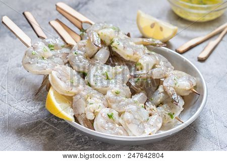 Raw Shrimps On Wooden Skewers With Yellow Lemon Slices