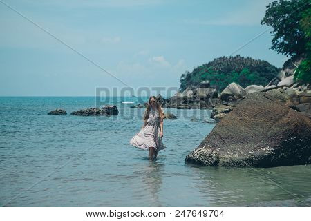 Handsome Girl On The Beach Background. Portrait Of A Woman In White Clothes On The Sea